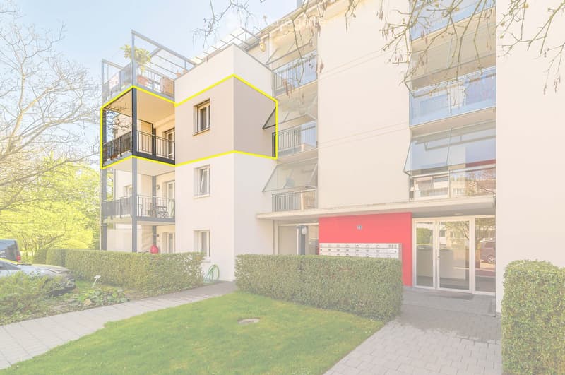 Modern multi-story residential building with balconies, glass railings, and a landscaped garden area.