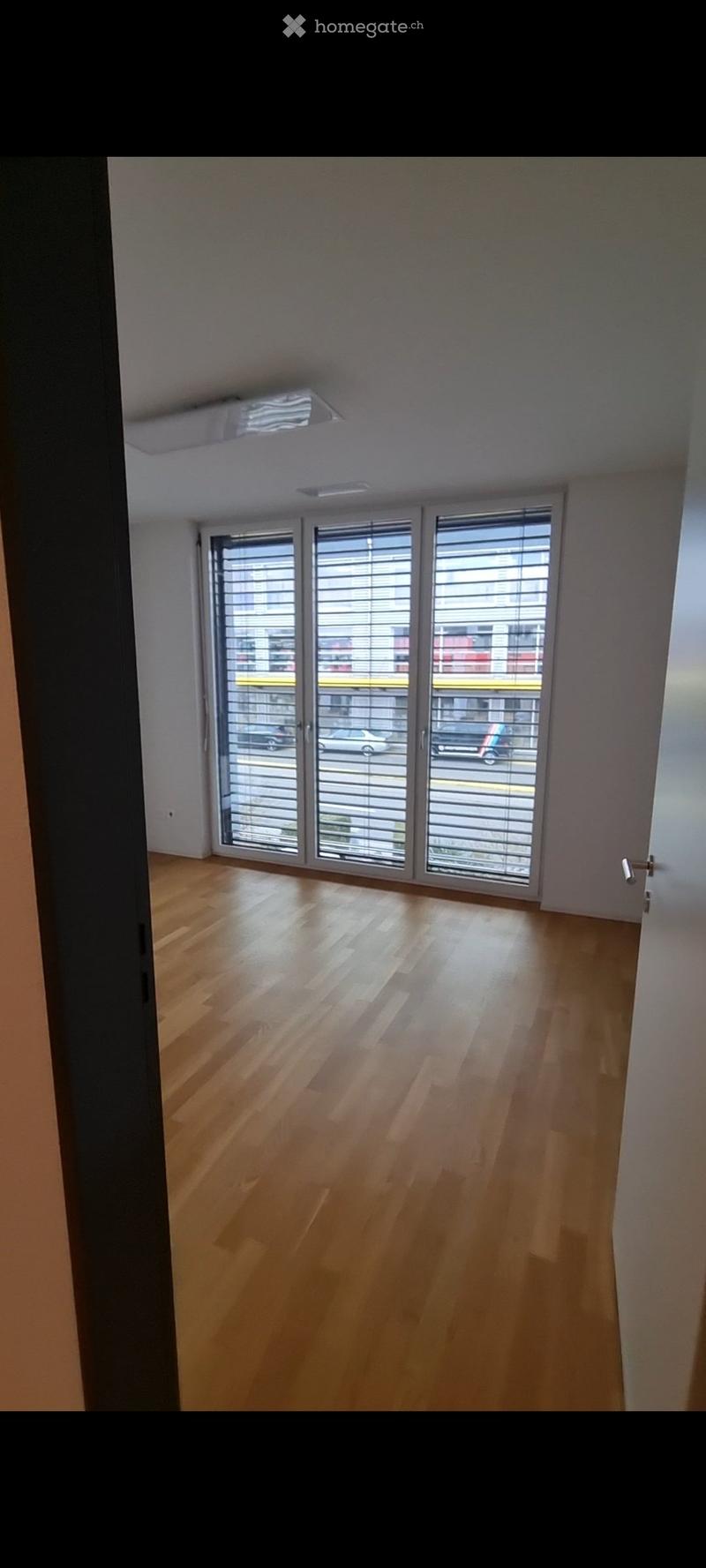 Empty room with wooden flooring and large sliding glass doors leading to a balcony. No furniture or equipment present.