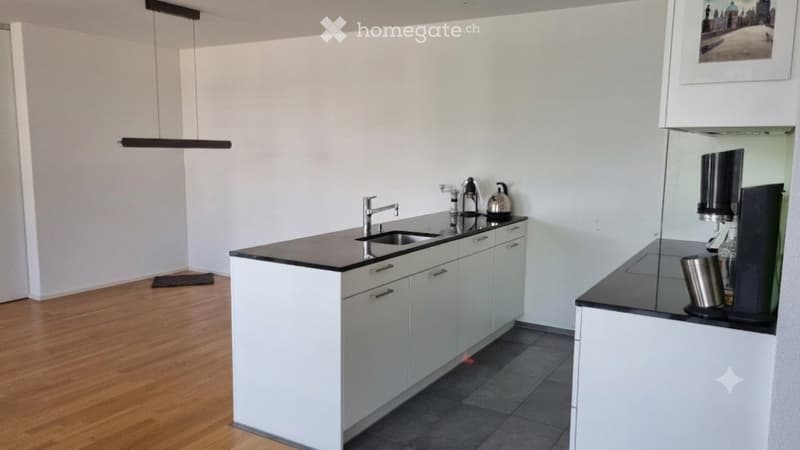 Modern kitchen with white cabinets, black countertops, a sink, a coffee maker, and a teapot on the counter.