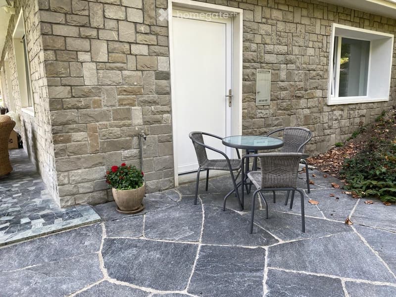 Stone wall house, white door, patio table and chairs, small flower pot