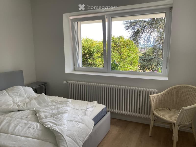 bedroom with bed, nightstand, chair, radiator, large window with outdoor view