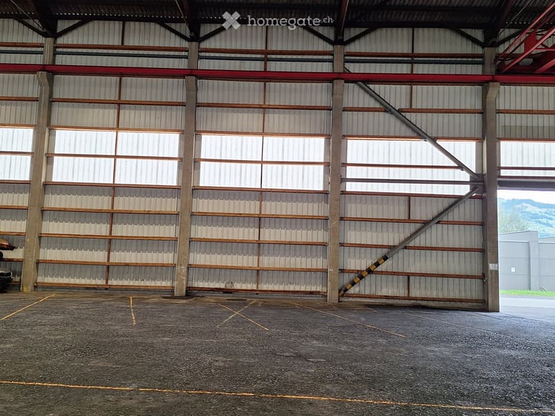 empty large room, concrete floor, large roll up doors, metal columns, large windows