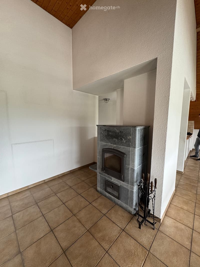 Empty hallway with tiled floor, white walls, and a built-in fireplace with a black metal fire tool set nearby.