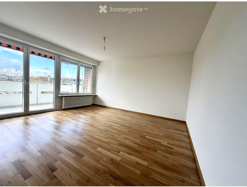 Empty room with wooden flooring, large windows, and white walls. No furniture or equipment present.