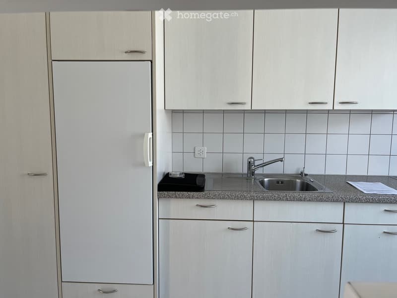 Modern kitchen with white cabinets, a stainless steel sink, and a granite countertop.