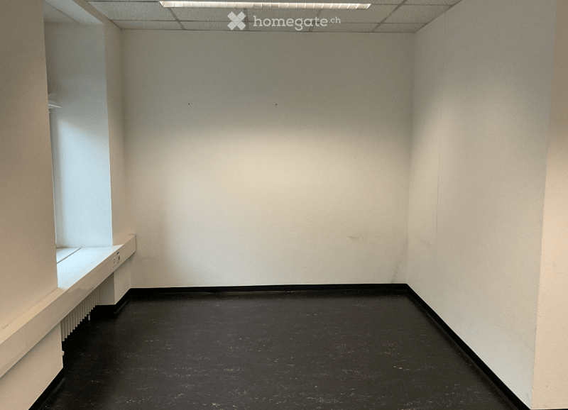 Empty room with white walls, black floor, and a small built-in shelf on the left side.