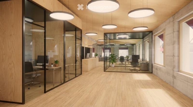 Modern office space with wooden flooring, glass partitions, desks, chairs, computers, and plants.