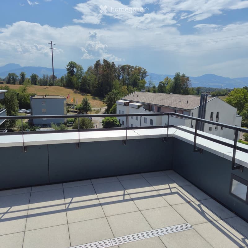 Balcony with tiled floor, metal railing, and scenic view of surrounding landscape and mountains.