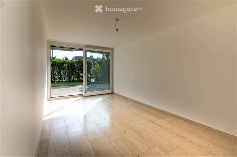 Empty room with white walls, tiled floor, and large sliding glass door leading to an outdoor area.