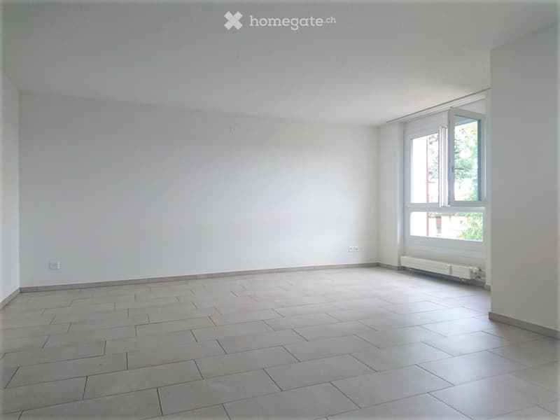 Empty room with tiled floor, white walls, and a large window with white frame. No furniture or equipment present.