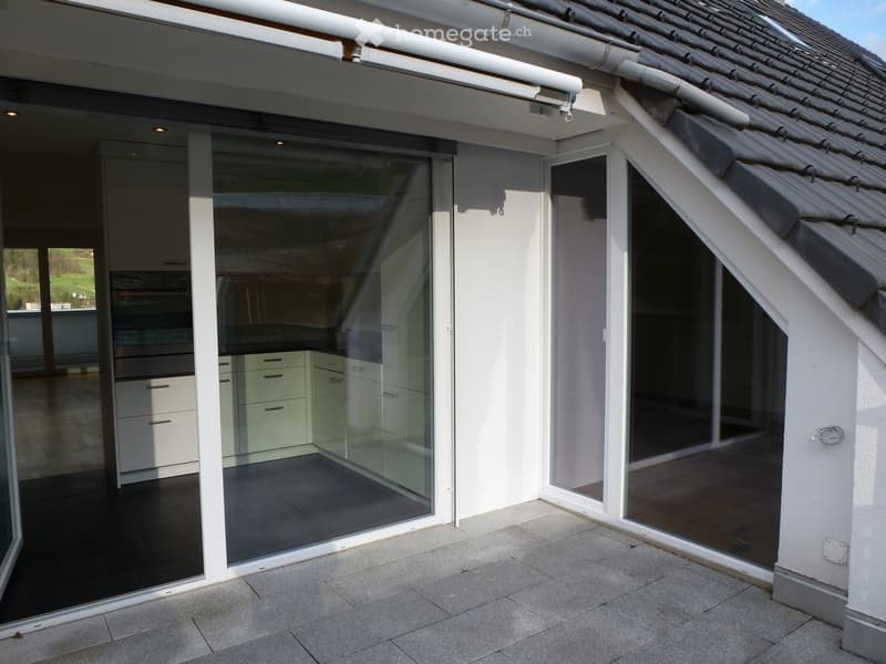terrace with sliding glass doors, tile floor, glass partition, white walls, kitchen inside, drawers, oven