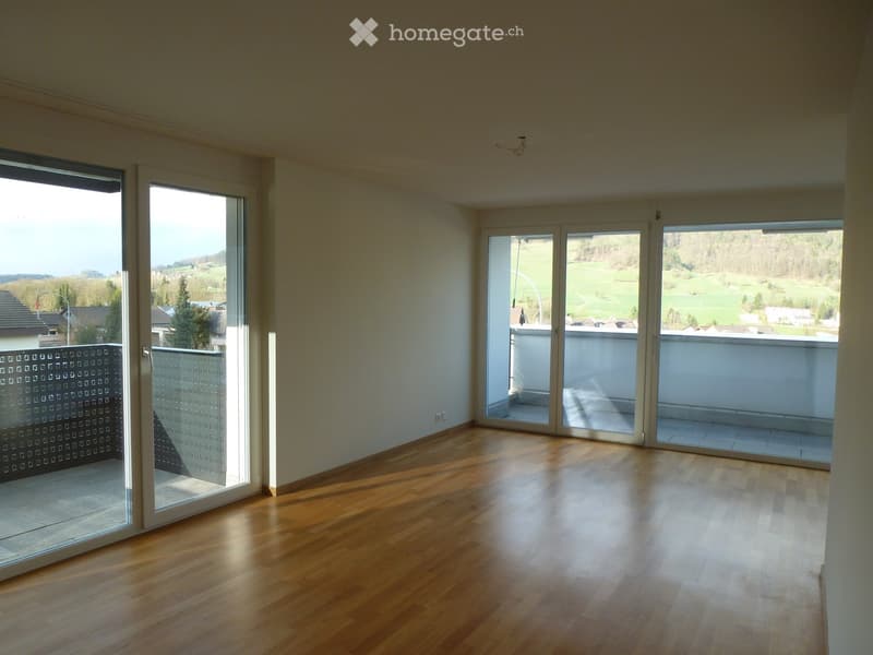 open plan room, large sliding doors to balcony, balcony railing, wooden floor, view of a green landscape