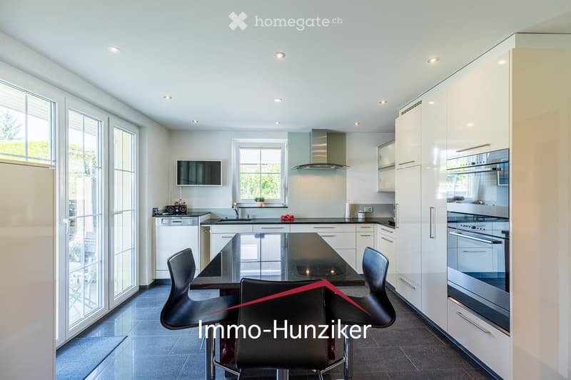 Modern kitchen with white cabinets, black countertops, stainless steel appliances, and a central island with a dining area.