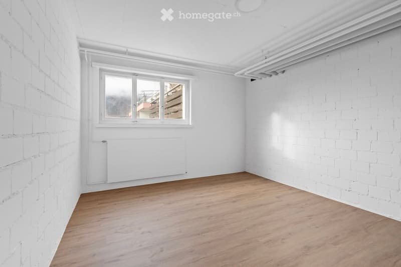 Empty room with white brick walls, wooden floor, a window and white radiator