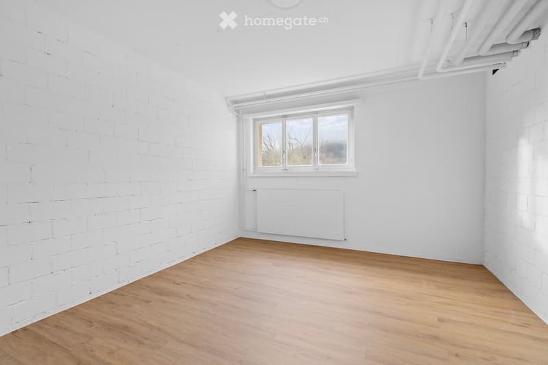 empty room with white brick walls, wooden floor, radiator, window