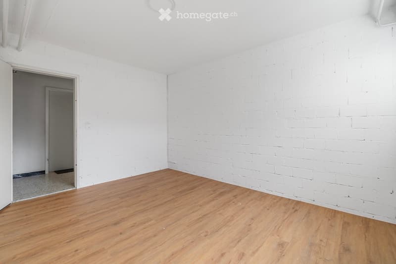 Empty room with wooden floor, white walls, doorway leading to another room, and a doorway leading to an outdoor space