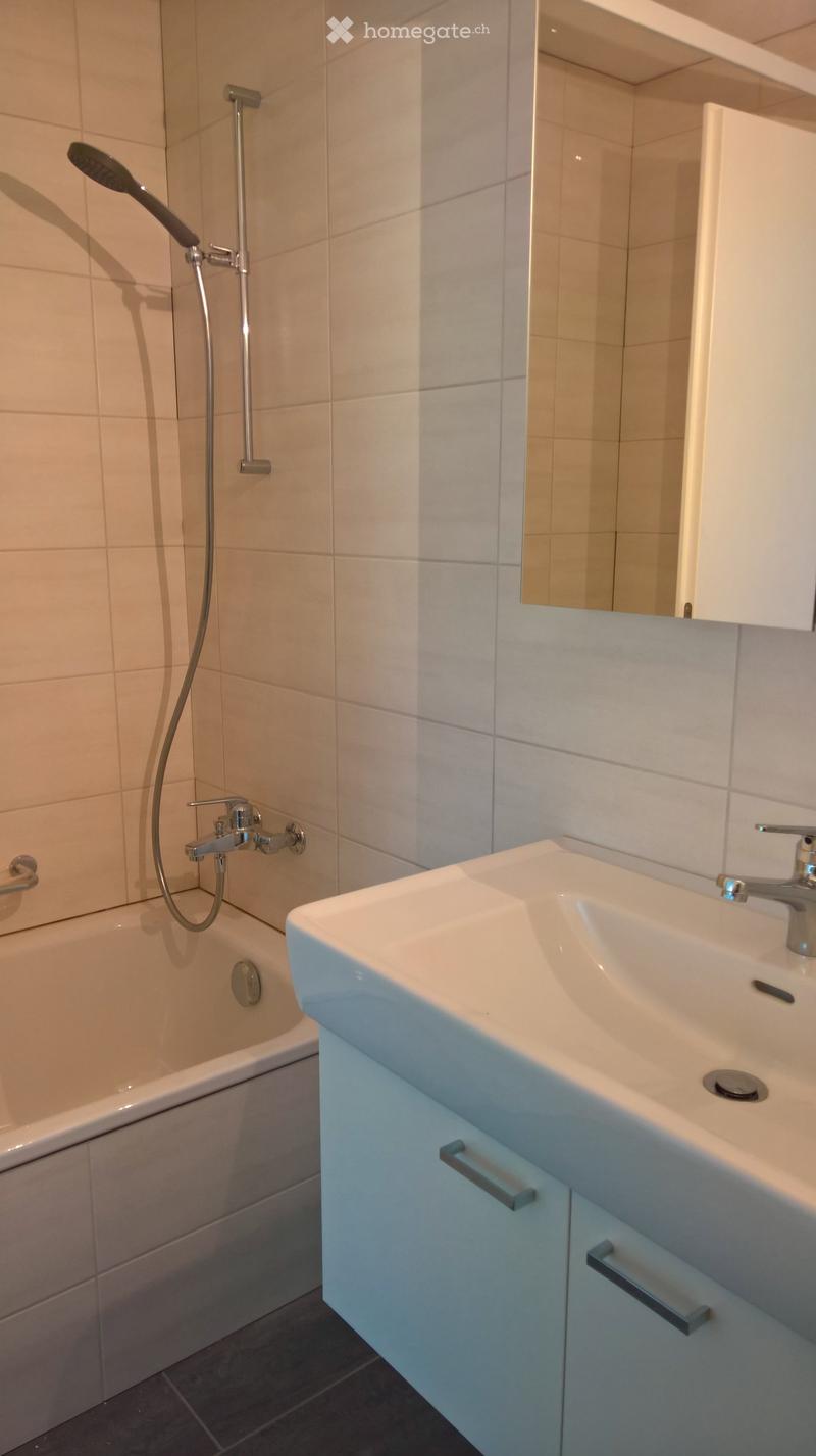 Modern bathroom with a bathtub, double sink, mirror, and showerhead.