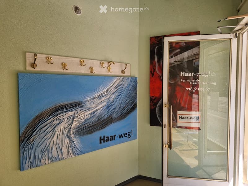Hallway with a coat rack, artwork, and a glass door with signage for 'Haar-weg!' and contact information.