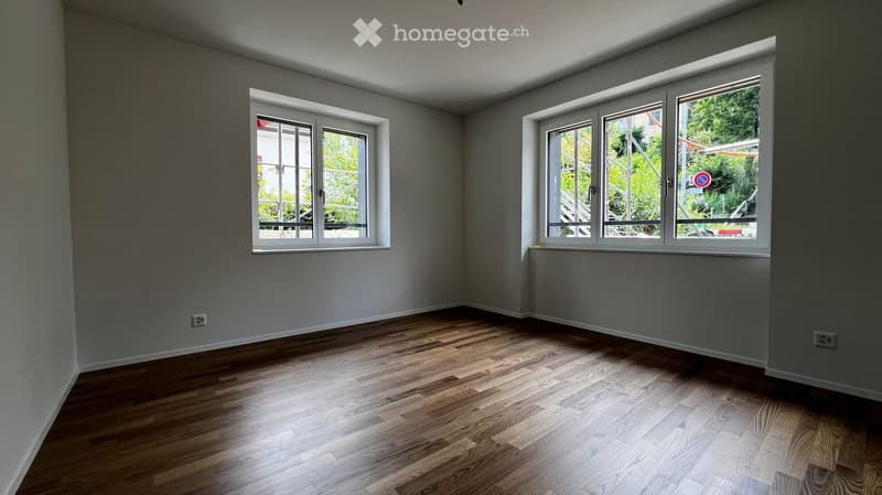 Empty room with wooden flooring and large windows, no furniture or equipment.