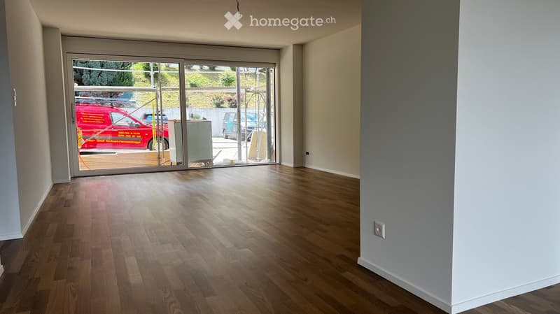 Empty room with wooden flooring and large glass sliding doors leading to an outdoor area. No furniture or equipment is present.