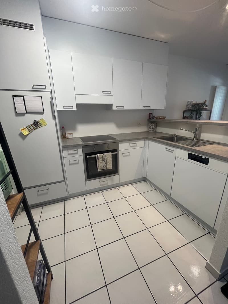 Modern kitchen with white cabinets, tiled floor, stainless steel oven, sink, and countertop.