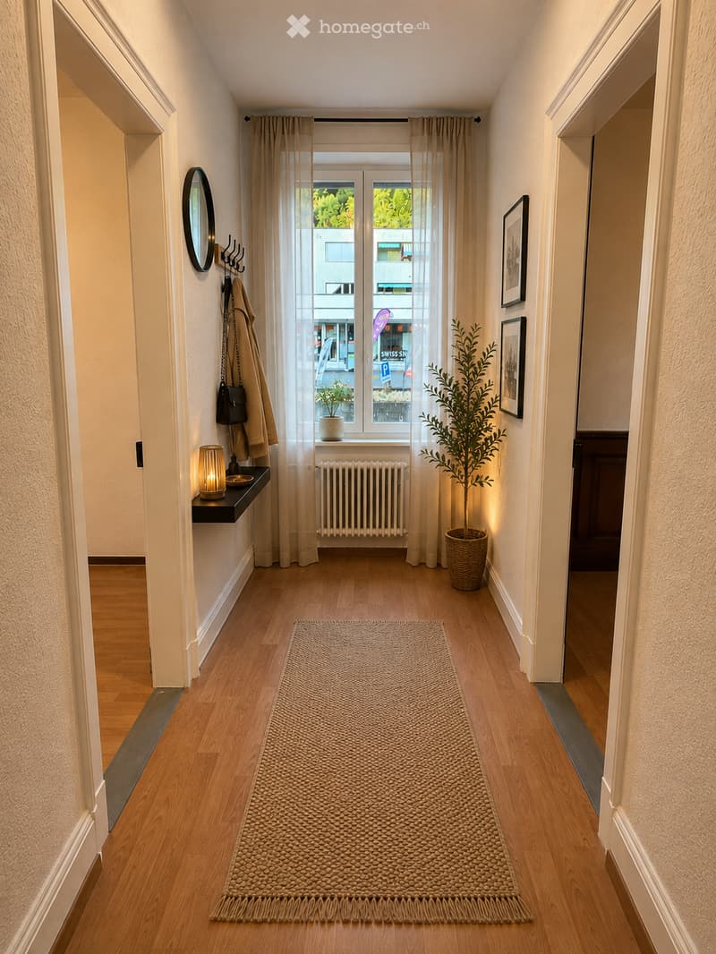 A well-lit hallway with wooden flooring, a woven runner rug, a small shelf with a candle, a coat rack with coats and bags, a potted plant, and framed artwork on the walls.