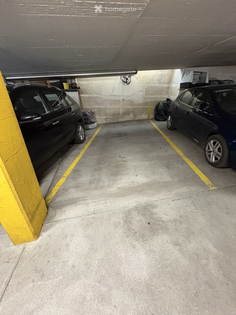 underground parking lot with two cars parked, yellow lines, yellow support beam