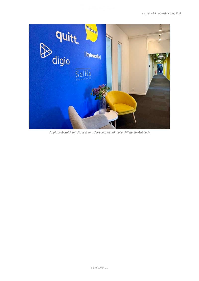 Reception area with a blue wall displaying logos, a yellow chair, a small round table with a vase of flowers, and a grey chair partially visible.