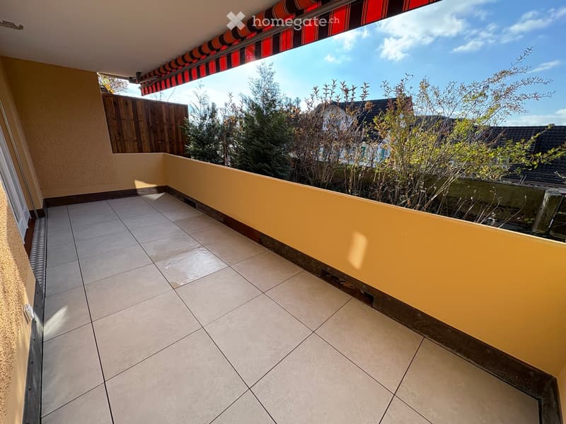 Tiled balcony, yellow walls, retractable awning, garden view
