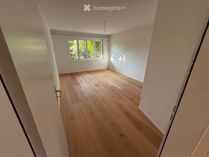 Empty room with hardwood floors and white walls, a window lets in natural light, room appears spacious.