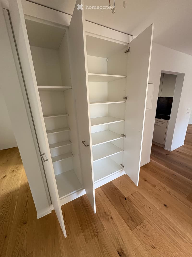empty white built-in closet with multiple shelves, wooden floor