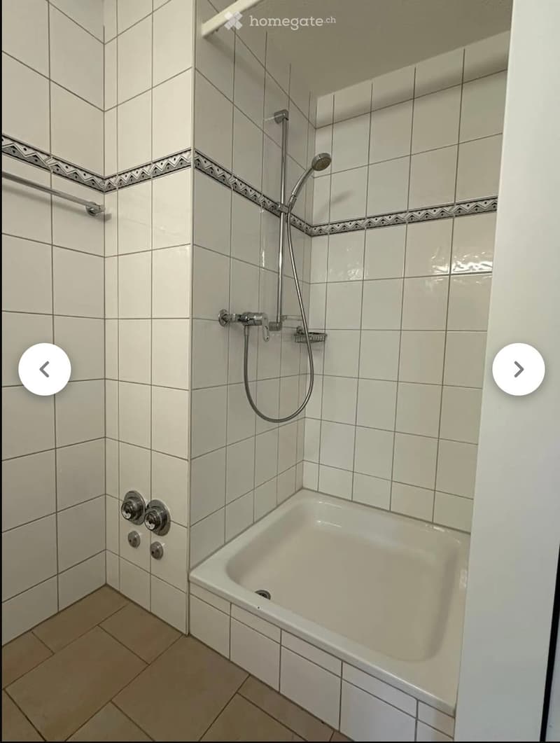 Bathroom with a bathtub, tiled walls, and a showerhead attached to the wall.