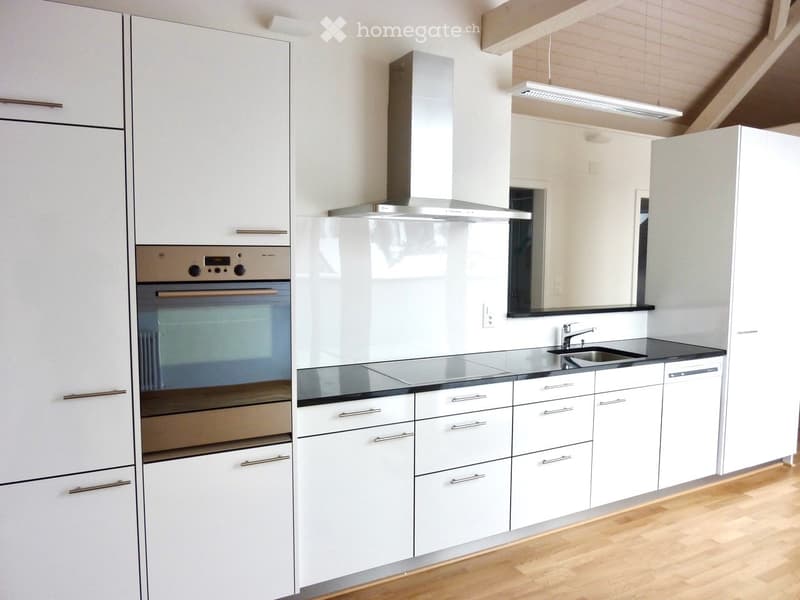 Modern kitchen with white cabinets, stainless steel appliances, and a black countertop.