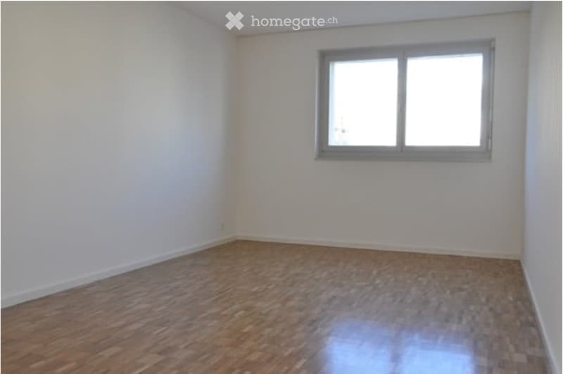 Empty room with wooden flooring and a single window, no furniture or equipment.