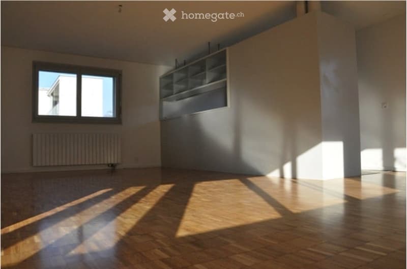 Empty room with wooden flooring, white walls, a window with white frame, and a built-in shelving unit on one wall.