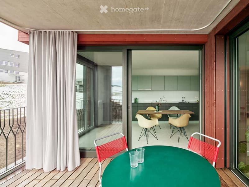 Balcony with wooden floor, glass doors, metal railing, table, chairs, curtains, view of the outside