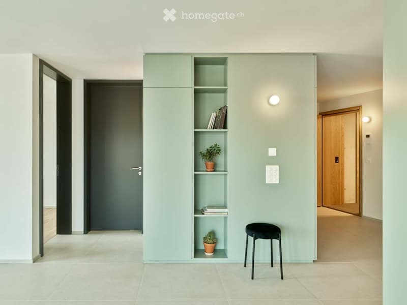 minimalist room with green walls, tiled floor, built-in shelves, black stool, wooden door, light fixtures