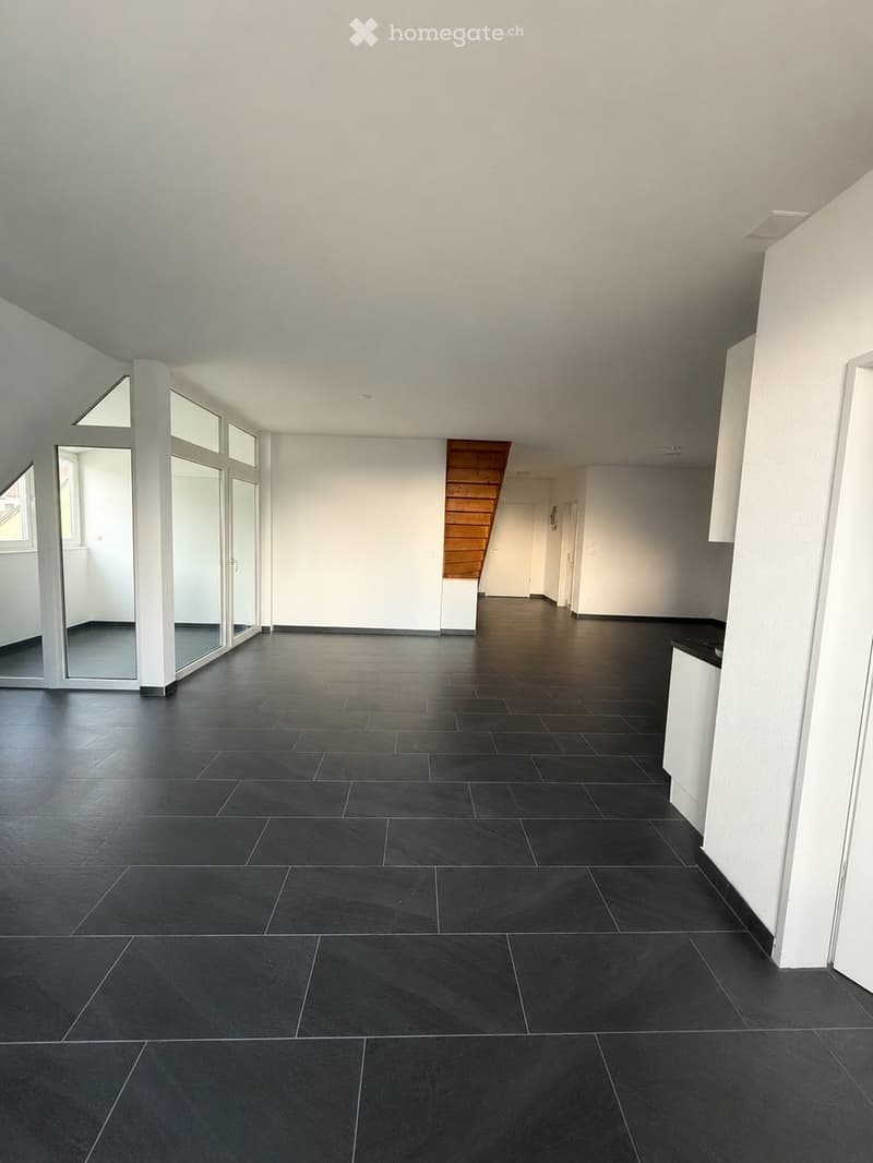 Completely empty room with bare walls and dark tiled floor. No furniture or equipment.