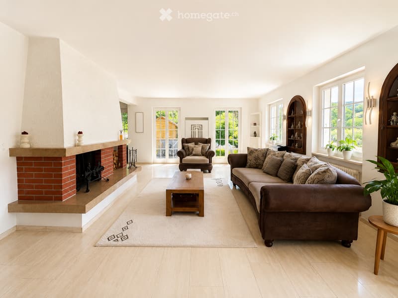 Bright living room with wooden flooring, large windows, a brick fireplace, a sofa, armchair, coffee table, and decorative plants.