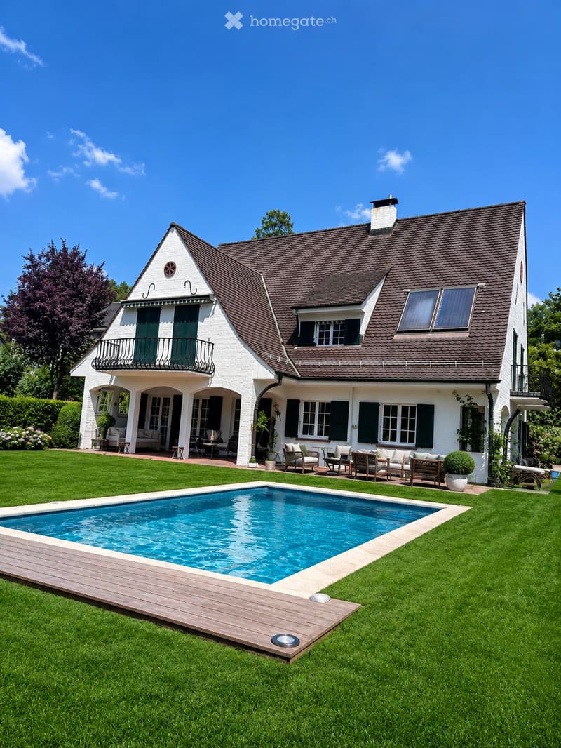 Two-story white house with dark brown roof, multiple windows, balconies, and a swimming pool in the front yard.