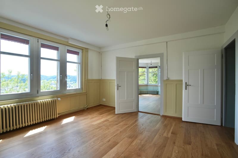 Empty room with wooden flooring, large windows, and white walls. No furniture or equipment present.