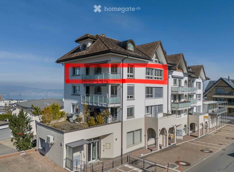 Multi-story residential building with balconies, large windows, and a scenic view of the surrounding area.