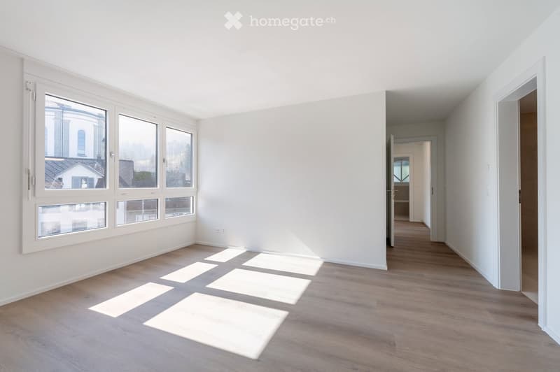 Empty room with white walls, wooden floor, and large windows. No furniture or equipment.