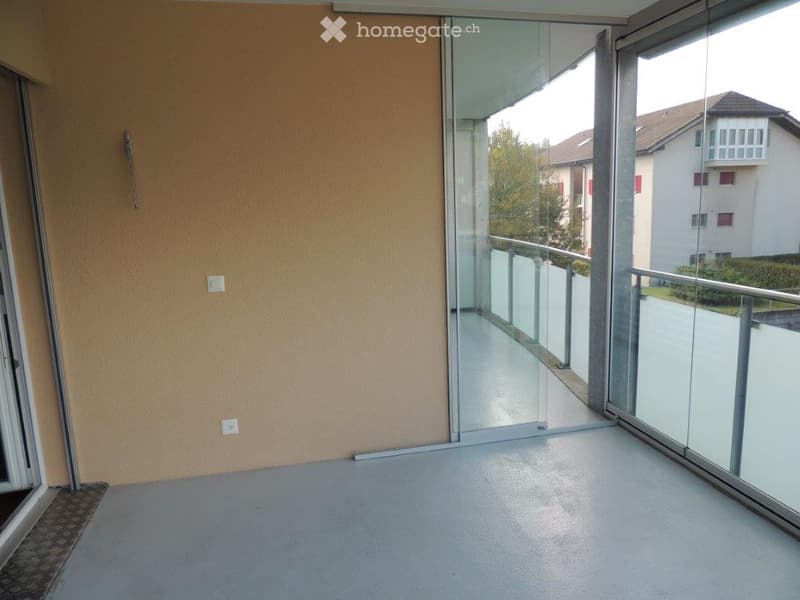 Empty room with large glass sliding doors leading to a balcony, light-colored walls, and a smooth floor.