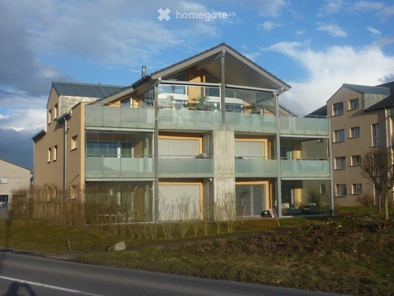 Modern two-story house with large glass balconies, contemporary design, and a clean facade.