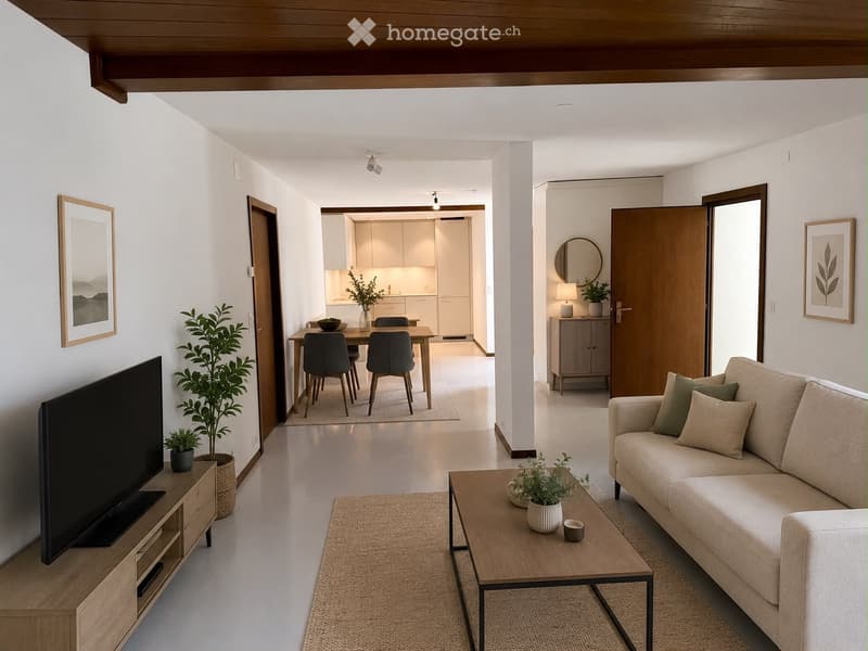 Modern living room with a beige sofa, coffee table, TV stand, dining area with a table and chairs, and a small kitchen area visible in the background. The space features light-colored walls, wooden flooring, and decorative plants.