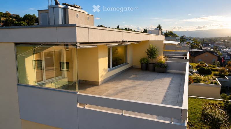 Modern rooftop terrace with tiled flooring, glass railing, potted plants, and scenic city and mountain views.
