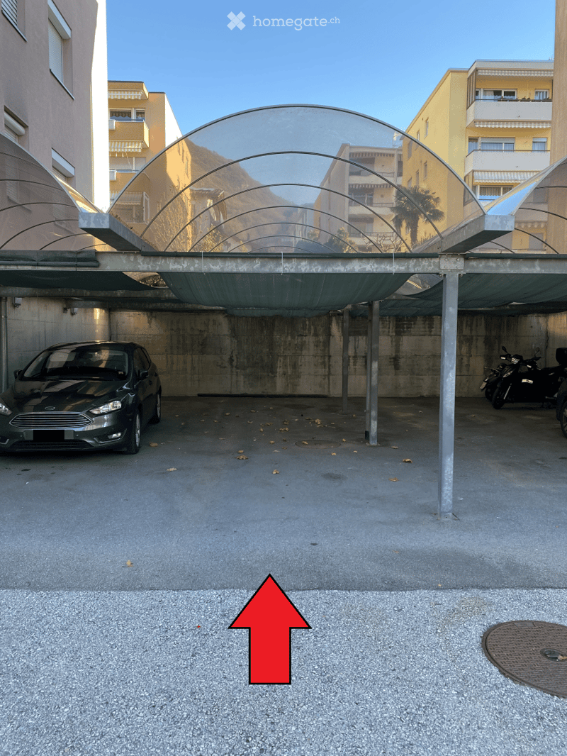 Underground garage with a modern, curved glass roof structure, featuring a parked car and motorcycles.