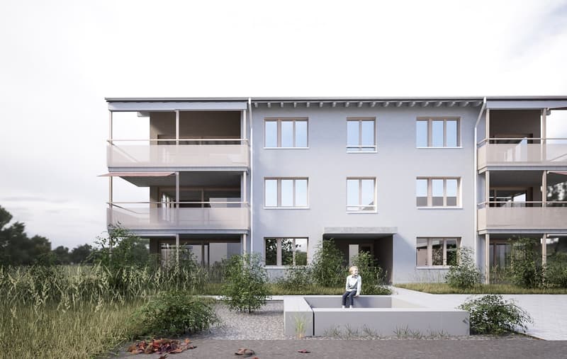 Modern two-story house with light gray facade, multiple windows, and balconies on both floors. The house is surrounded by greenery and a paved pathway leads to the entrance.