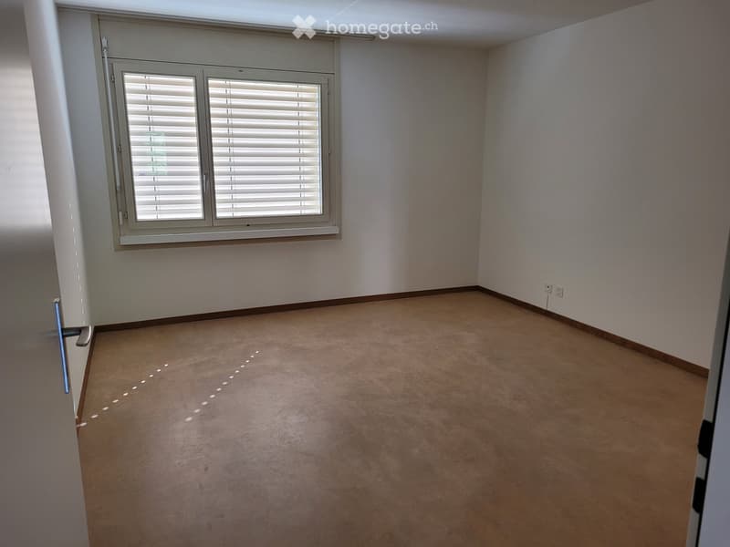 Empty room with beige tiled floor, white walls, and a window with blinds. No furniture or equipment present.